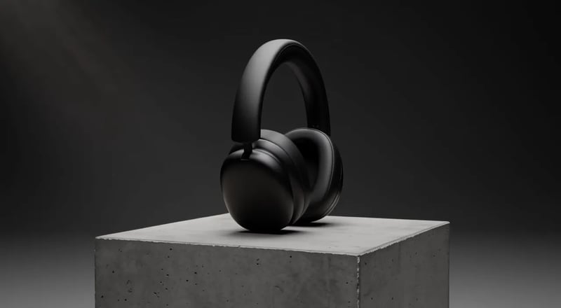 FLUX 3: cuffie over-ear nero opaco su un piedistallo di cemento, viste di profilo e poi frontalmente sotto una luce fredda e neutra